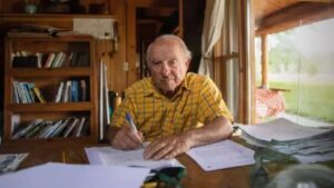 Imagem de Yvon Chouinard, bilionário que doou fortuna, sentado à mesa.