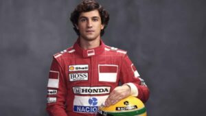 Gabriel Leone, ator da série sobre Ayrton Senna na Netflix, sentado segurando o capacete do piloto, representando o ícone da Fórmula 1.