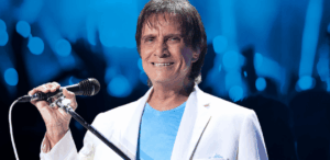 Roberto Carlos sorrindo ao microfone durante especial de fim de ano na TV, em negociação com a Globo após fim de contrato exclusivo.