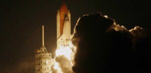 ançamento noturno de um foguete da NASA, iluminando o céu com sua propulsão e deixando uma grande nuvem de fumaça na decolagem.