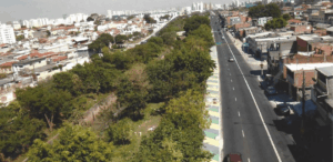Vista aérea do Parque Linear de Tiquatira com vegetação densa na Zona Leste de São Paulo, ao lado de avenida urbana.