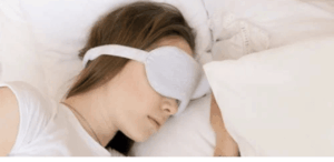 Mulher dormindo com máscara de olhos, representando a busca por qualidade do sono para manter a saúde da tireoide em equilíbrio.