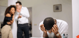 Homem com expressão de angústia em ambiente escolar, enquanto colegas ao fundo comentam em tom de deboche, representando o combate ao bullying