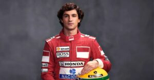 Ator caracterizado como Ayrton Senna na minissérie, vestindo macacão vermelho de corrida e segurando capacete com cores do Brasil