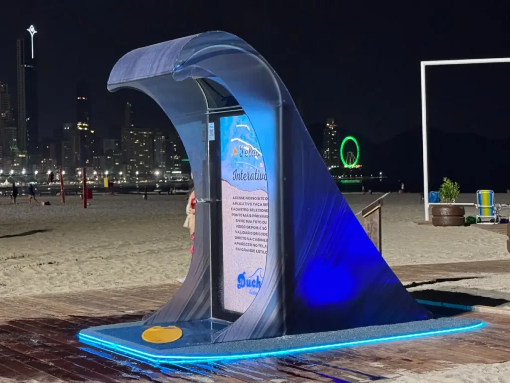 Ducha ecológica com design de onda instalada na Praia Central de Balneário Camboriú, com LED e painel informativo.