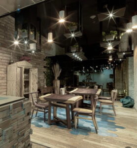 Ambiente do Restaurante Xal com mesas rústicas e iluminação suave em espaço que valoriza o design artesanal e cultural