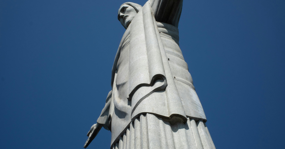 Vista impressionante do Cristo Redentor no Rio de Janeiro, capturada de baixo para cima, destacando sua grandiosidade e imponência.