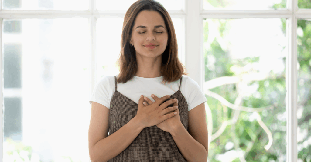 Mulher com a mão no peito e olhos fechados, expressando gratidão e serenidade.