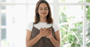 Mulher com a mão no peito e olhos fechados, expressando gratidão e serenidade.