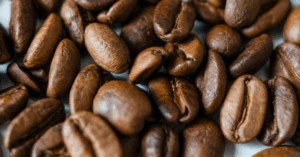 Grãos de café torrados espalhados sobre uma superfície.