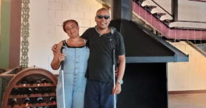 Casal com deficiência visual posa sorridente com bengalas brancas