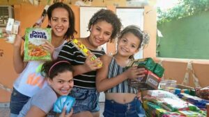 Crianças comemoram recebimento de alimentos e produtos no Eco Mercado, projeto do NEAC que promove inclusão social por meio da troca de recicláveis em Campo Grande (RJ).
