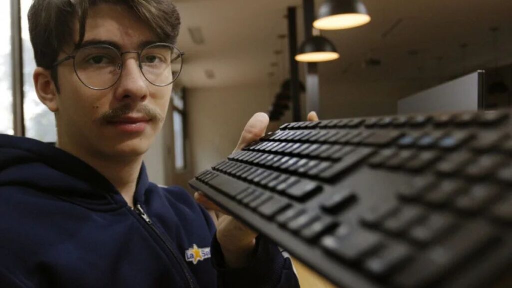 Estudante na olimpíada de IA na China segura teclado com expressão confiante.