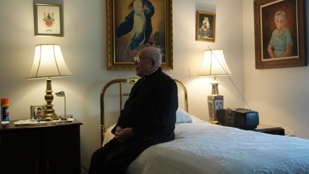 Padre de 100 anos em seu apartamento na comunidade Normandy Farms, celebrando sua missão com fé e serenidade.
