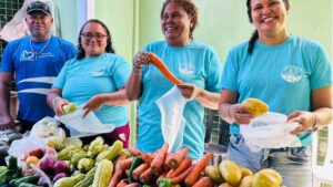 Agricultores e voluntários do projeto Meta MOH Fome exibem alimentos frescos em feira comunitária, simbolizando segurança alimentar no Brasil.
