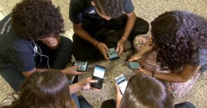 Jovens usando celular em grupo, representando a importância do ECA Digital para a proteção infantil online
