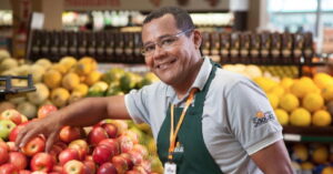 Colaborador do Grupo São Luiz no setor de hortifrúti organiza frutas frescas em unidade no Ceará.