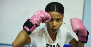 Mulher com luvas de boxe rosas durante aula de defesa pessoal para mulheres no Rio de Janeiro.