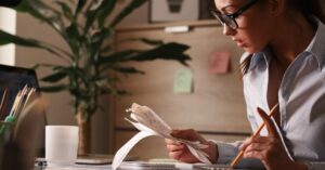 Imposto de Renda 2026 - Mulher calculando despesas e impostos no escritório.