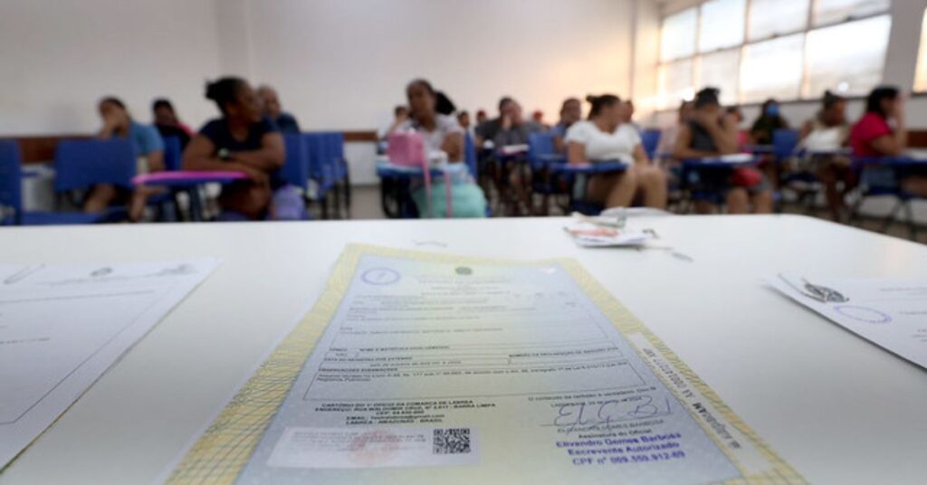certidões online - certidão de nascimento sobre mesa com pessoas ao fundo aguardando atendimento