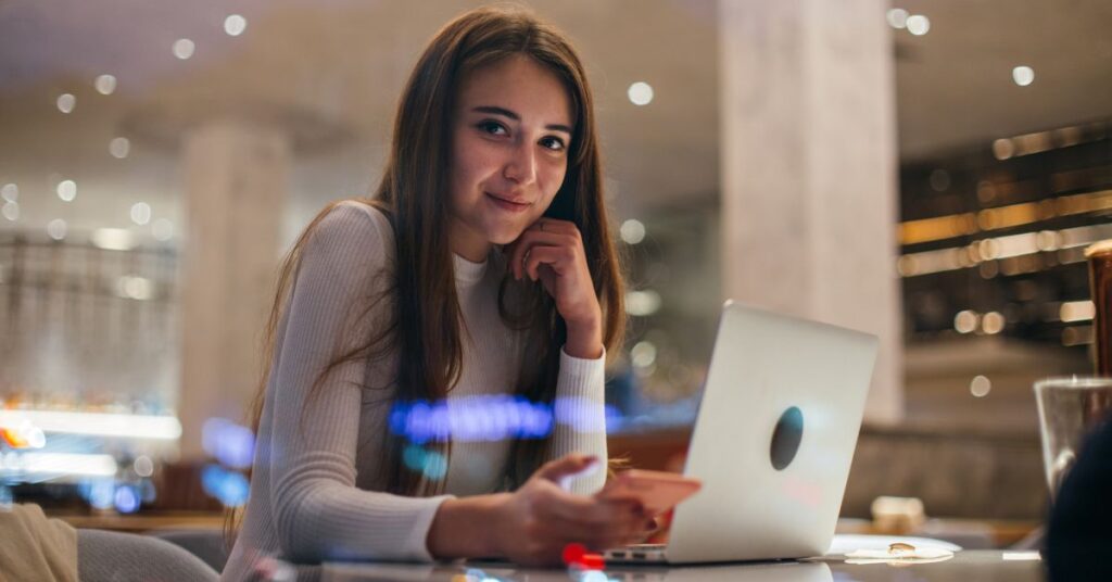 Empreendedora usando IA para MEI em seu laptop em um café moderno