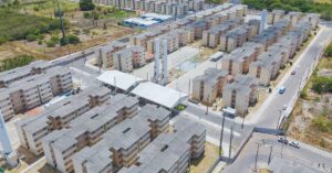 Conjunto habitacional do programa Minha Casa Minha Vida visto de cima, com prédios populares e área de convivência.