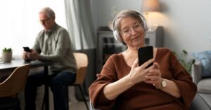 Adultos usam telemóvel em casa, ilustrando o crescimento do Uso Internet em Portugal