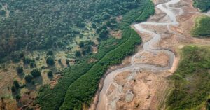 Floresta amazônica ao lado de área degradada com rio em estágio de seca avançada mostra os impactos da crise climática.