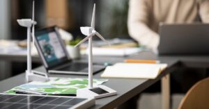 investimento em ações climáticas no Brasil - Modelos de turbinas eólicas e painéis solares sobre mesa de trabalho