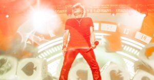 Imagem do Guns N’ Roses em ação no palco destacando estradas de luz e energia, usada para ilustrar cobertura de shows internacionais no Brasil 2026 com referência histórica à passagem da banda por Curitiba na Pedreira Paulo Leminski em outubro de 2025.