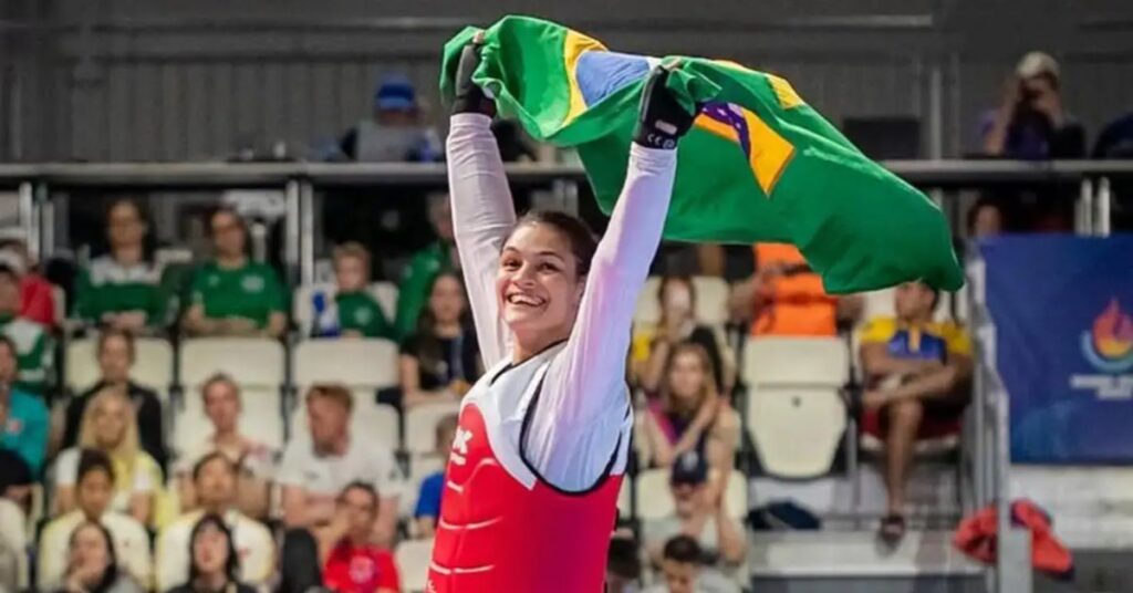 Atleta do esporte olímpico brasileiro comemora título mundial de taekwondo com a bandeira do Brasil