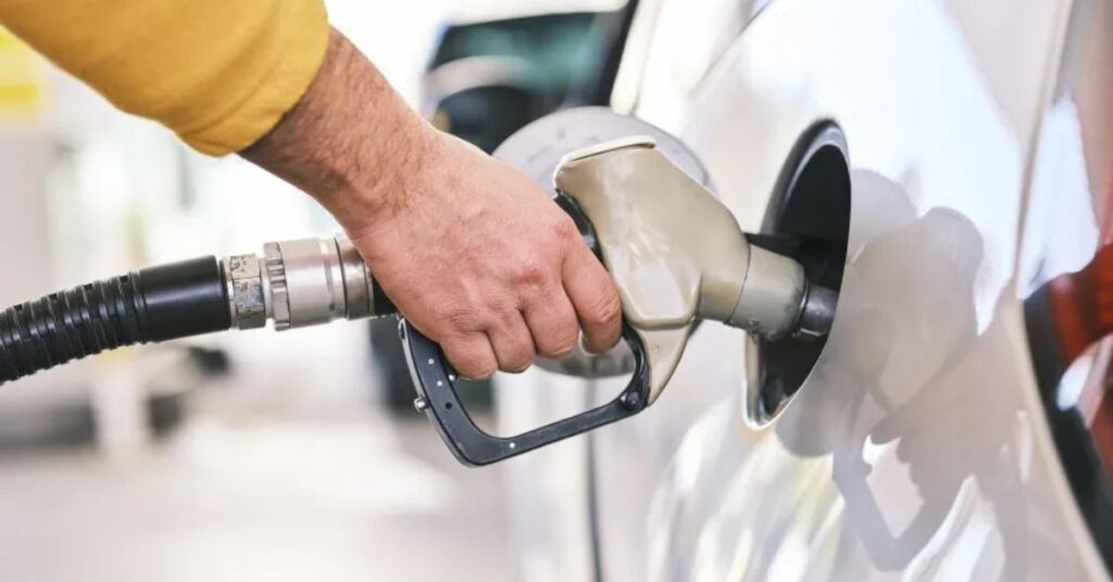 Mão abastecendo veículo em posto de combustível, ilustrando o preço da gasolina em novembro.