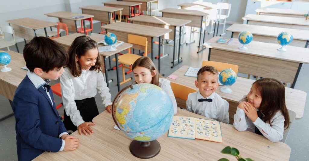 Crianças em sala de aula participam de atividade de ensino bilíngue na infância com material educativo e globo terrestre