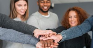 Equipe diversa celebrando igualdade de gênero nas empresas com união de mãos
