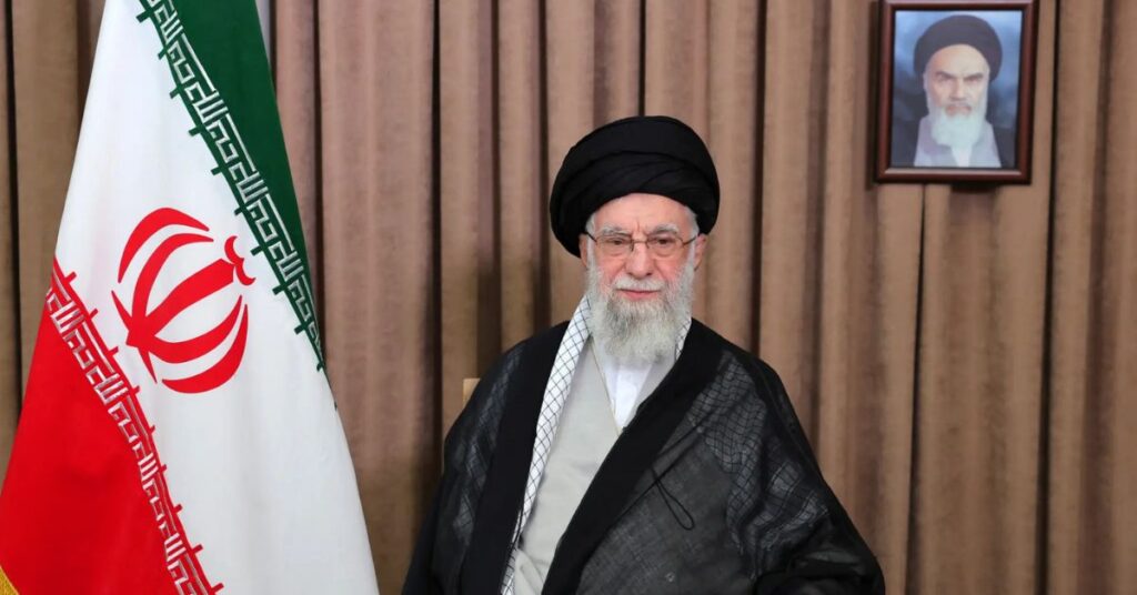 líder supremo do Irã sentado diante da bandeira iraniana